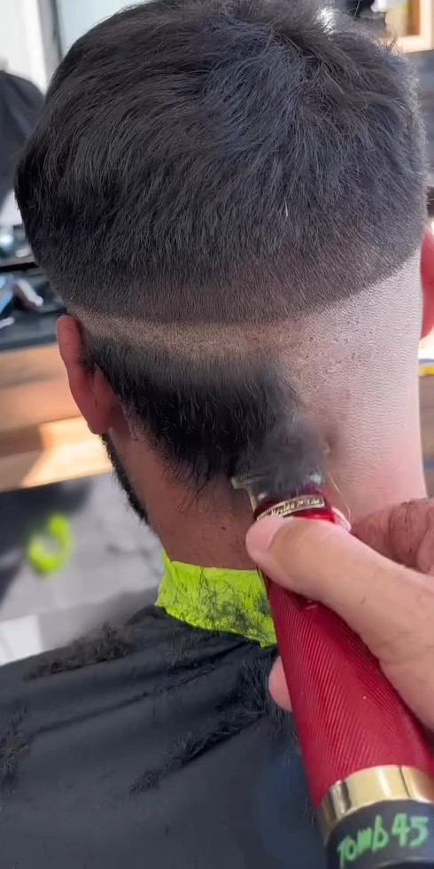 Een barber zet met de tondeuse een strakke lijn in de nek